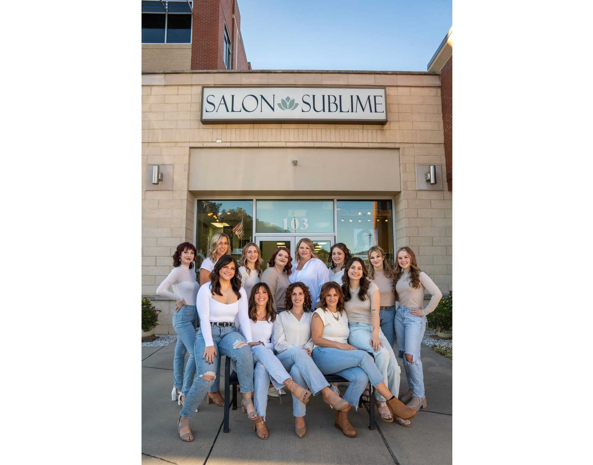 Group of 12 women posing in front of Salon Sublime in casual attire.