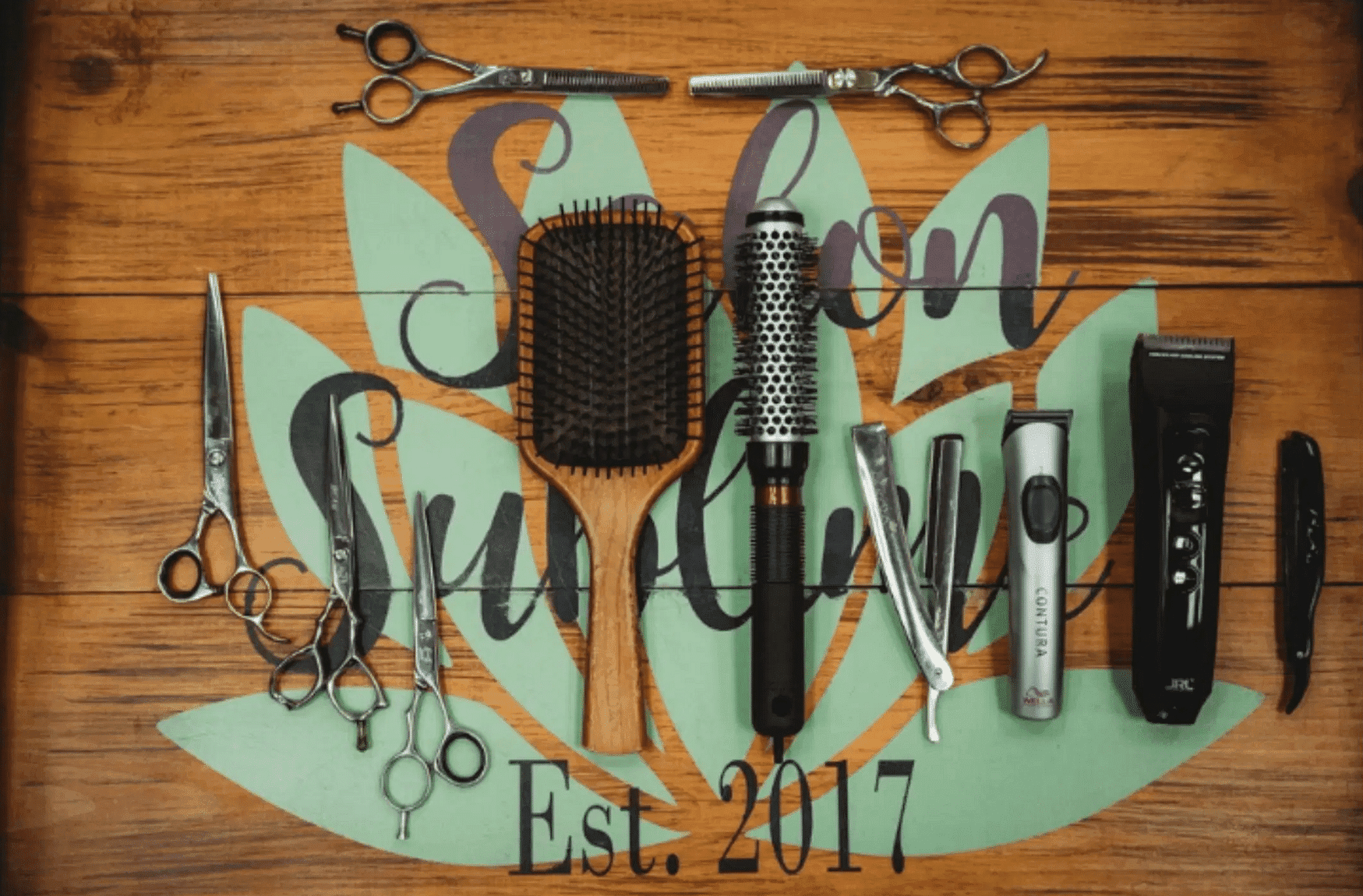 Hairdressing tools arranged on a wooden surface with a sign reading "Salon Sunshine, Est. 2017.